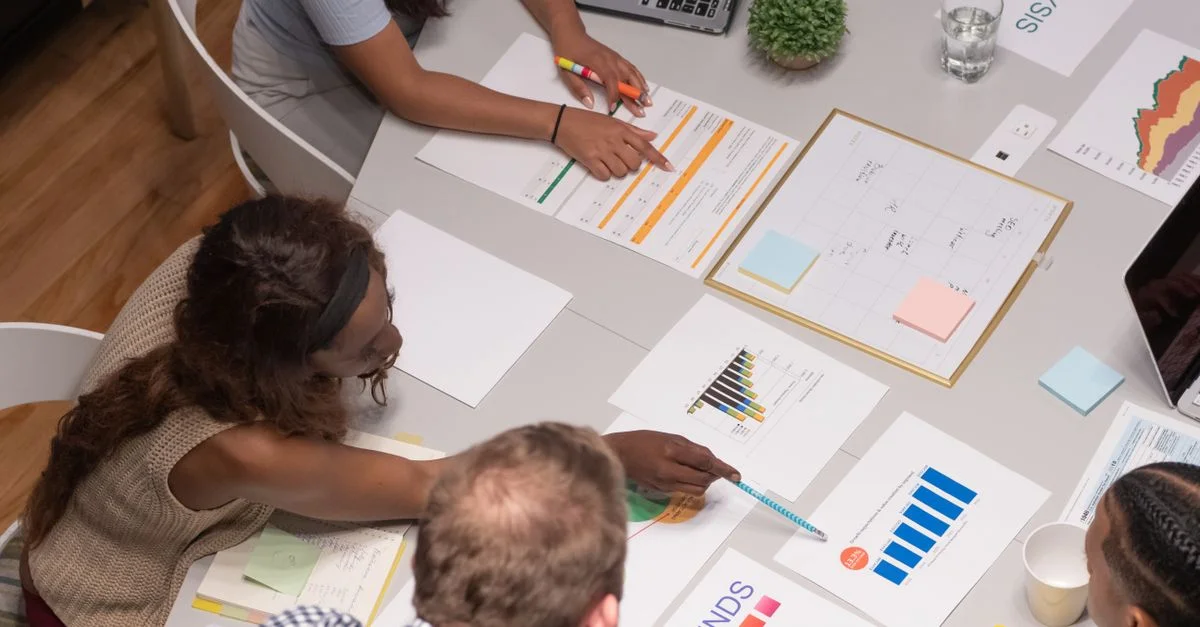 Équipe de professionnels collaborant sur un projet d'affaires, analysant des graphiques et des diagrammes dans un cadre de bureau.