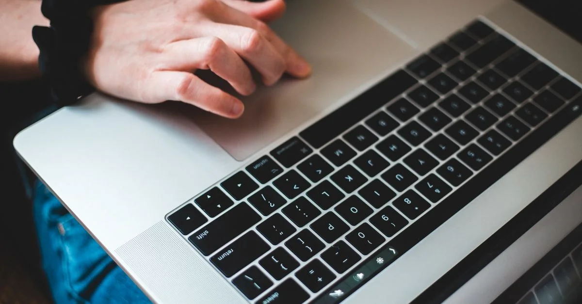 Personne tapant sur un clavier d'ordinateur portable, se concentrant sur les mains et l'utilisation de la technologie moderne.