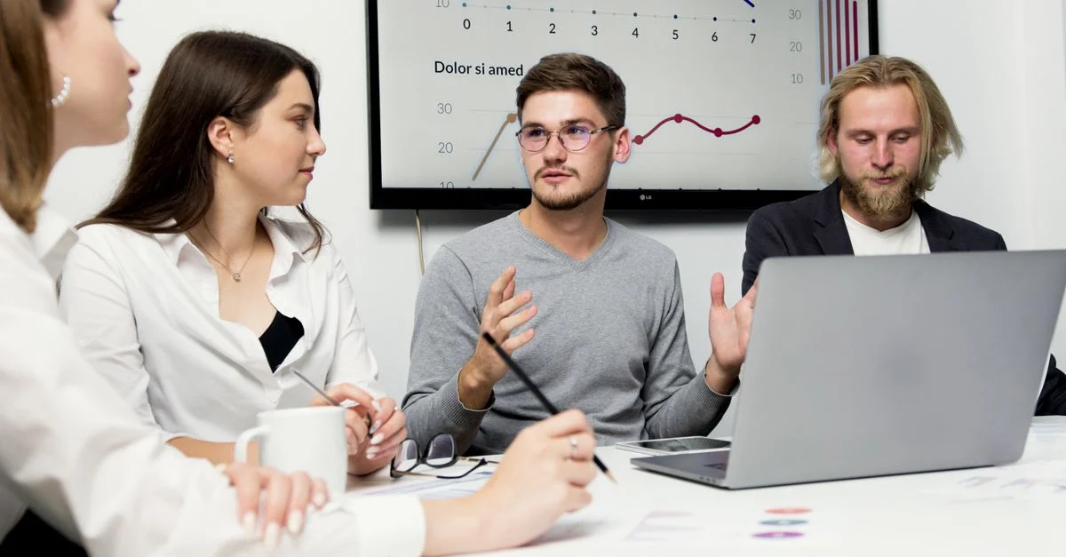 Groupe de collègues discutant stratégie avec des graphiques en arrière-plan.
