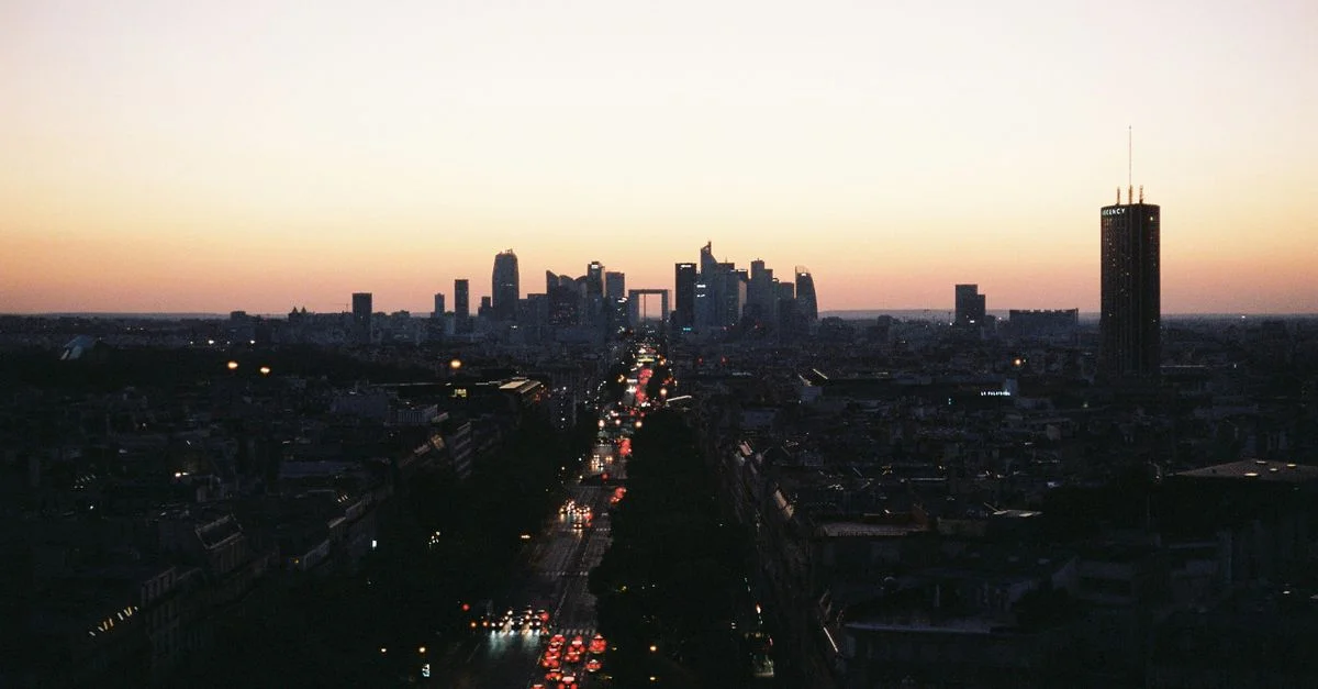 Une vue aérienne époustouflante d'une ligne d'horizon de ville avec des gratte-ciel en silhouette contre un coucher de soleil éclatant.