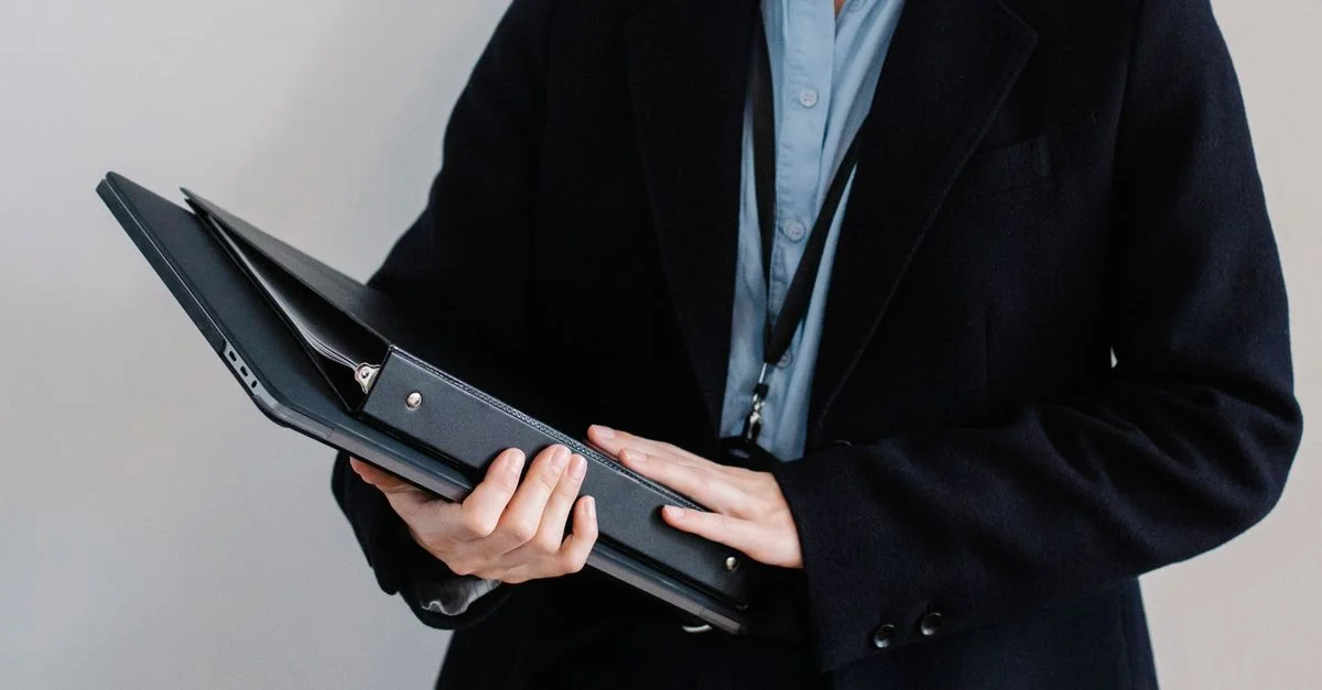 Professionnel des affaires en tenue formelle tenant un dossier dans un cadre de bureau.