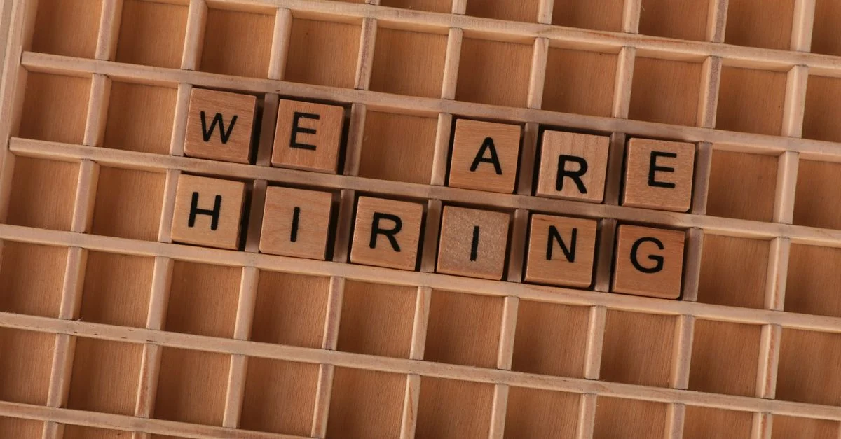 Panneau de tuiles en bois formant la phrase « Nous recrutons », idéal pour les annonces d'emploi.