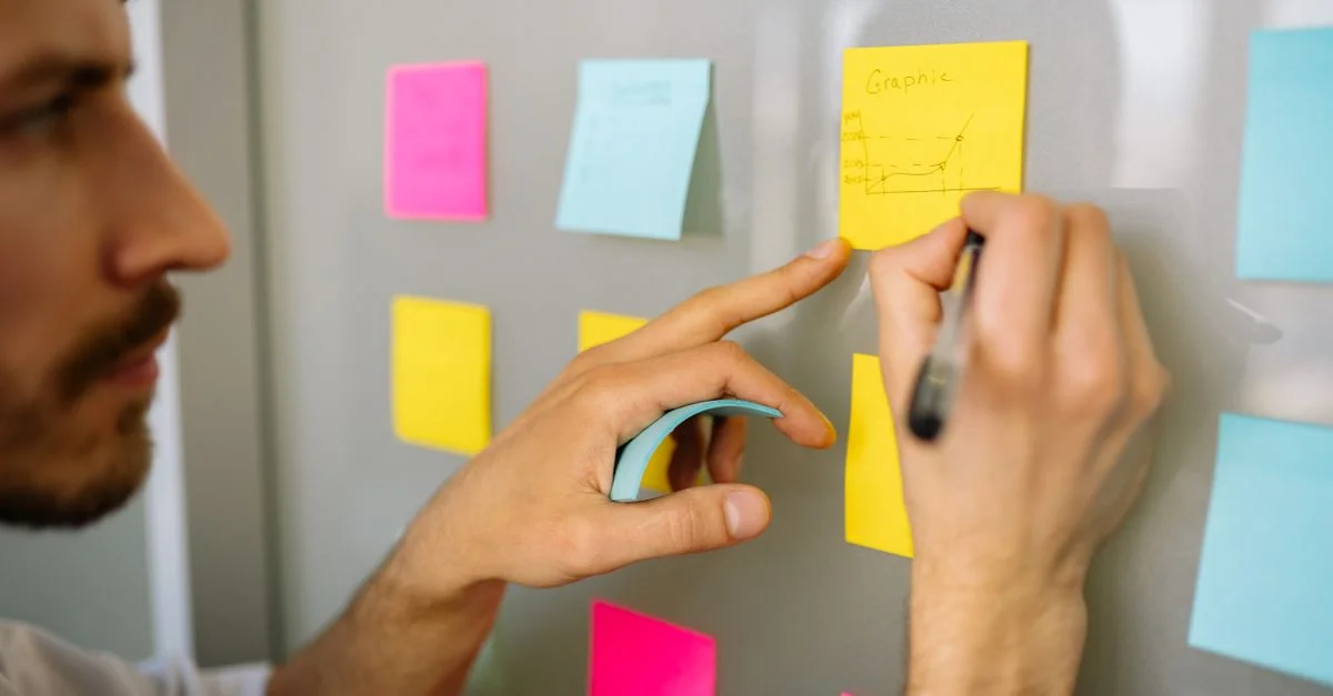 Homme d'affaires concentré écrivant des idées sur des post-it pour la planification et l'organisation.