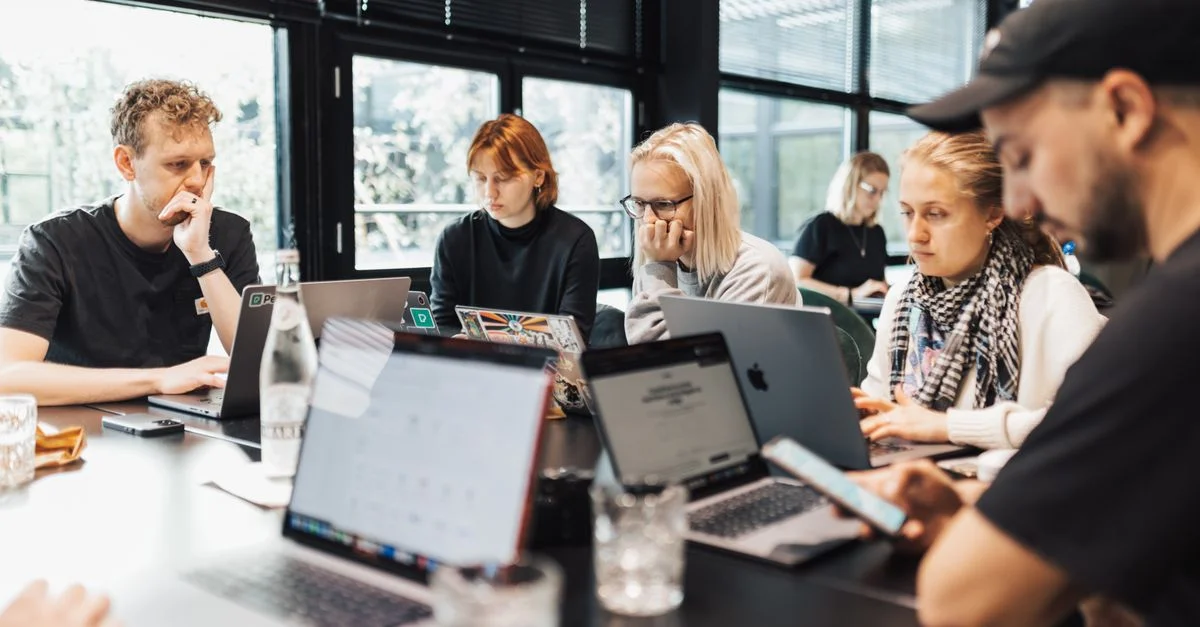 Un groupe de professionnels engagé dans un travail numérique sur des ordinateurs portables et des smartphones dans un environnement de bureau moderne.