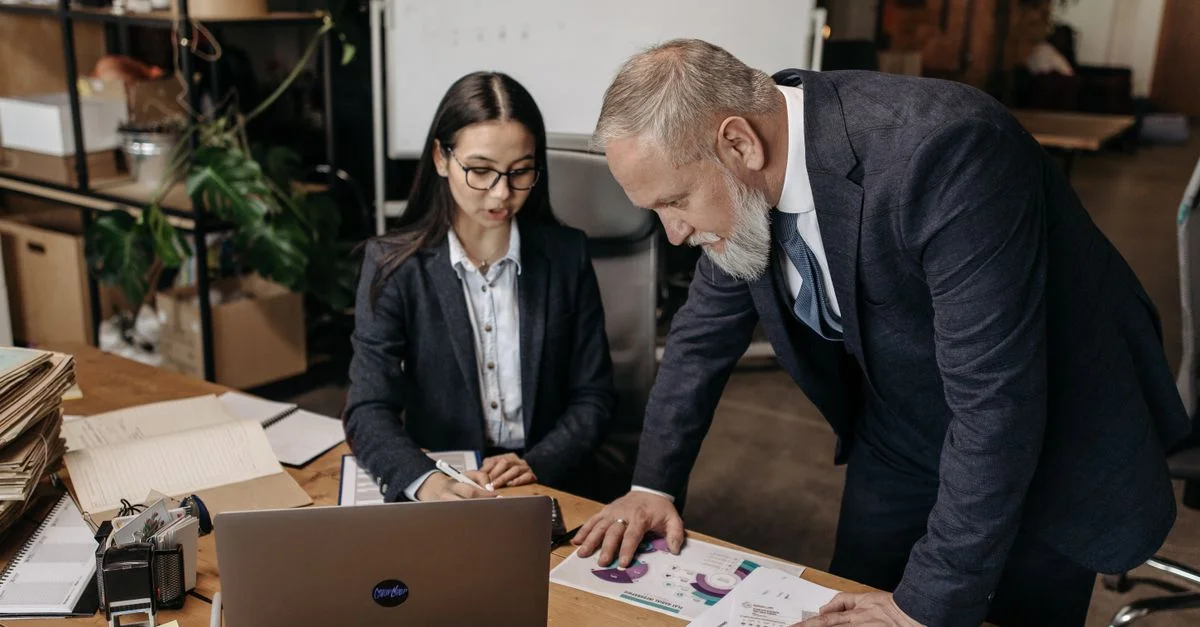 Réunion d'affaires avec deux professionnels discutant de graphiques et de données à un bureau.