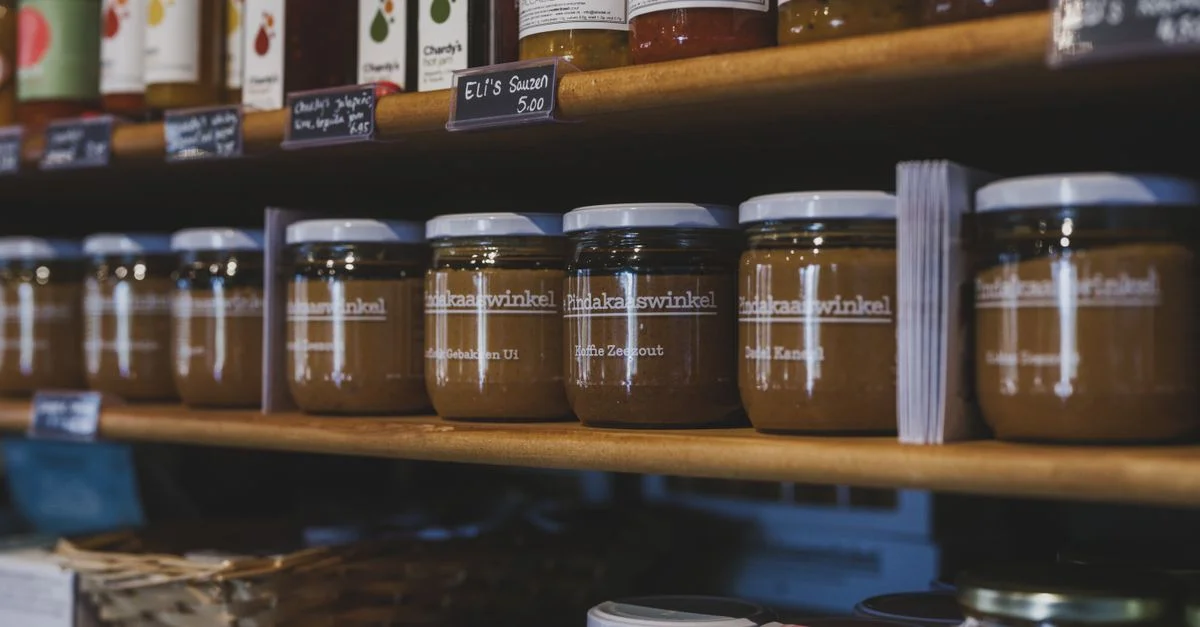 Gros plan de bocaux alimentaires artisanaux sur des étagères en bois dans une boutique locale à Almere, Pays-Bas.