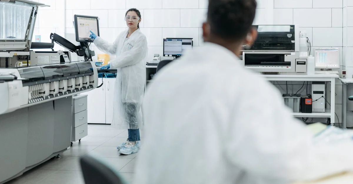 Des scientifiques dans un environnement de laboratoire utilisant des écrans et portant des équipements de sécurité.