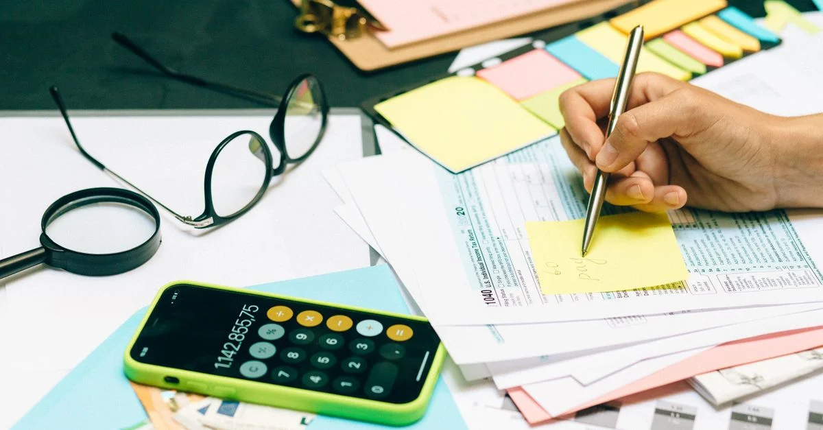 Gros plan sur un bureau avec une calculatrice, des lunettes et des documents pour la planification financière.